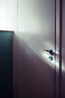 Minimalist luxury door handle in matte black with warm gold accents glowing softly.