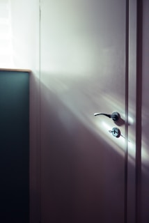 A minimalist white door with a subtle texture, bathed in soft afternoon light.