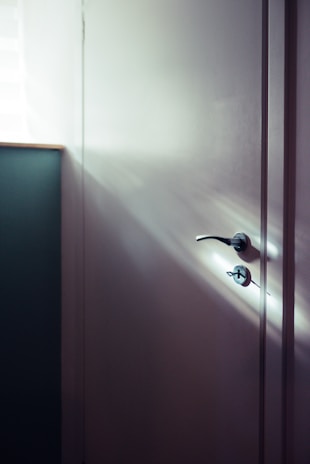 A minimalist white door with a subtle texture, bathed in soft afternoon light.
