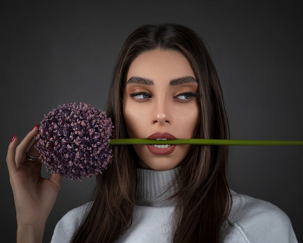 Mujer con camisa blanca sosteniendo una flor rosa