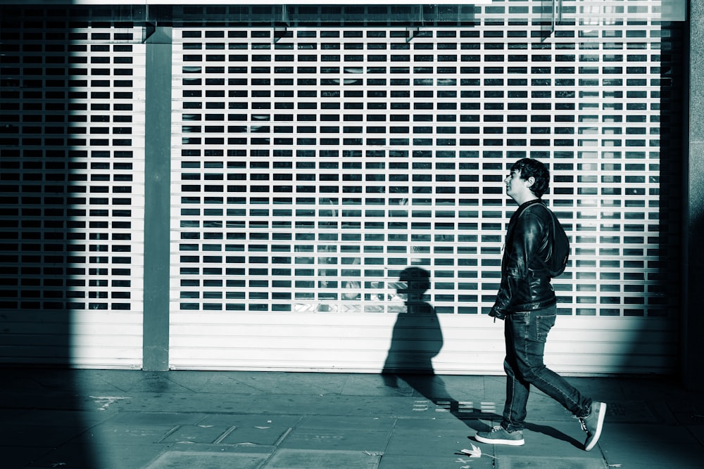 man in black jacket and pants walking on sidewalk