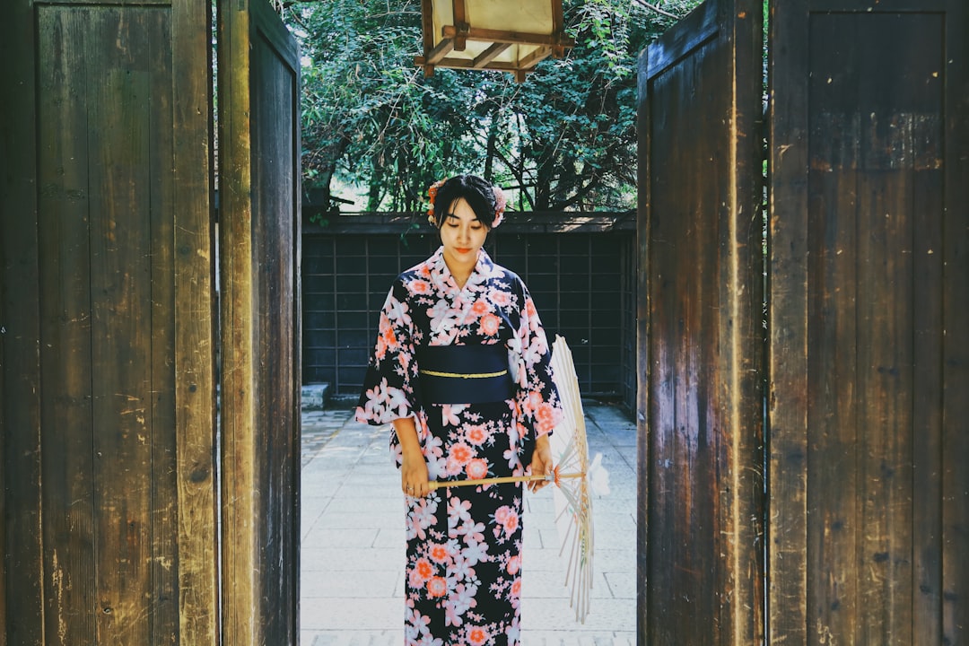 woman in black white and red floral kimono standing near brown wooden door