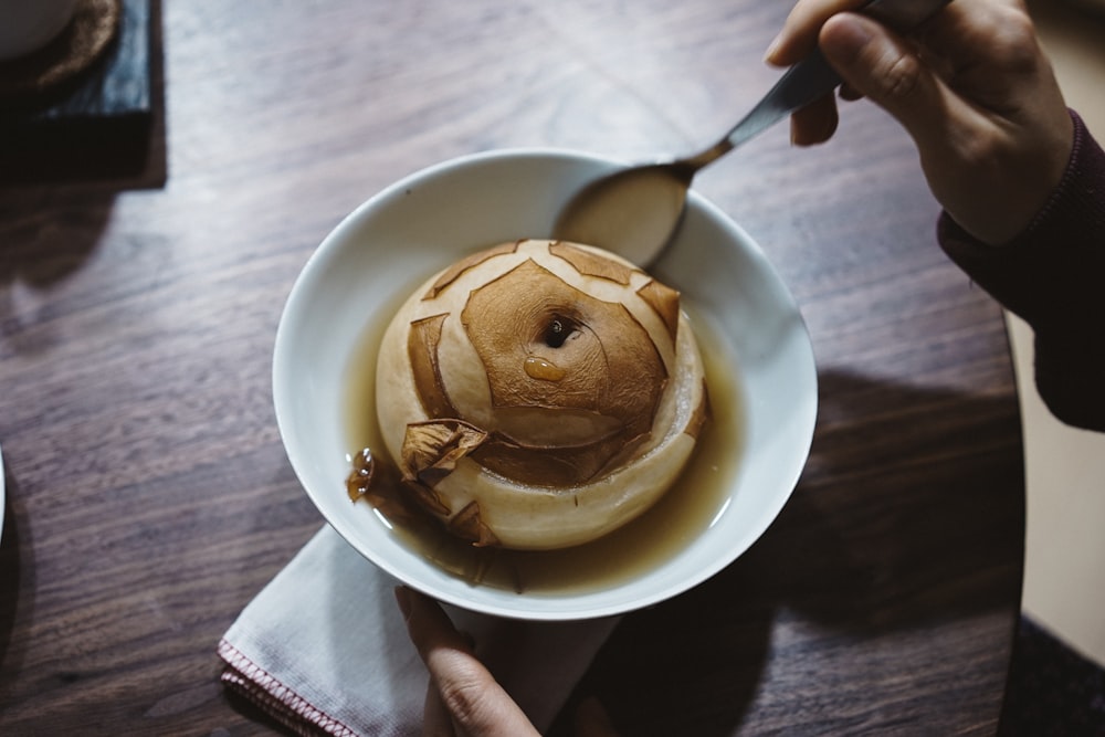 person holding white ceramic bowl with ice cream