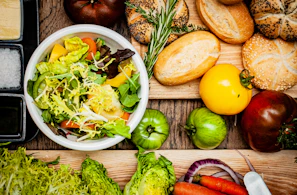 A vibrant bowl of fresh mixed salad with colorful vegetables and herbs, styled on a rustic wooden table.