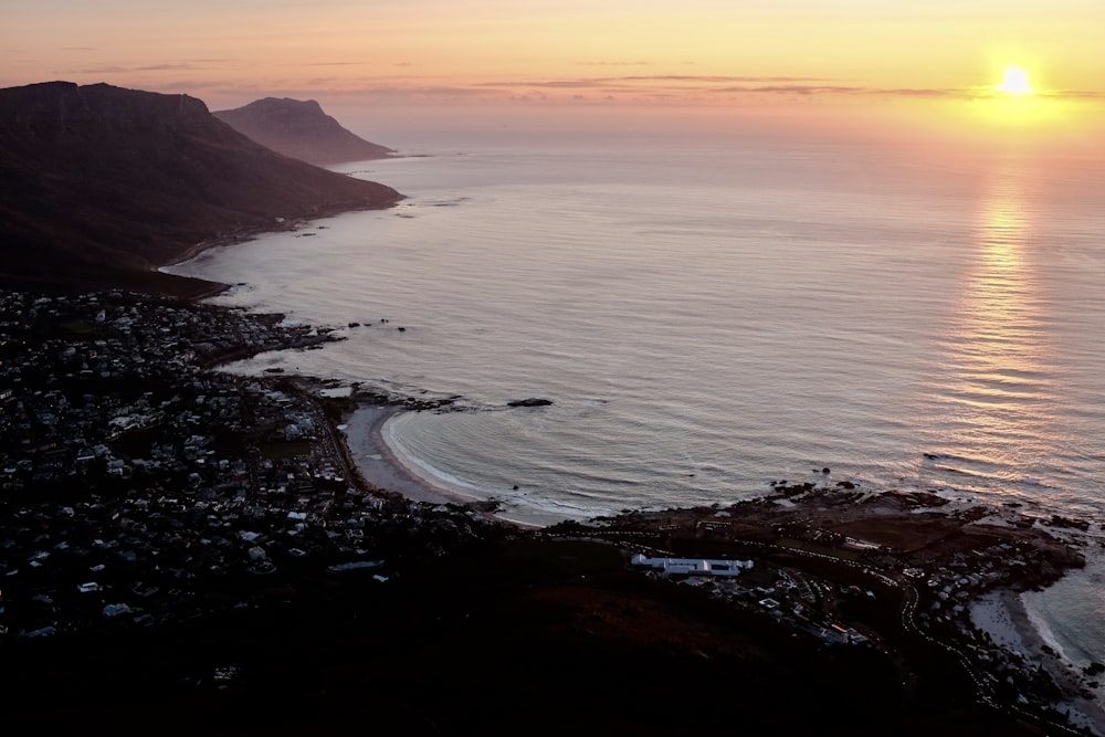 body of water near mountain during sunset