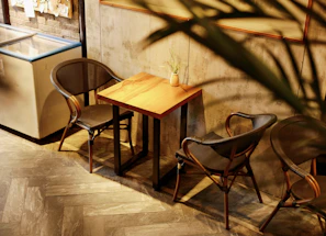 A cozy café setting featuring a rustic wooden table with metal legs, surrounded by comfortable chairs.