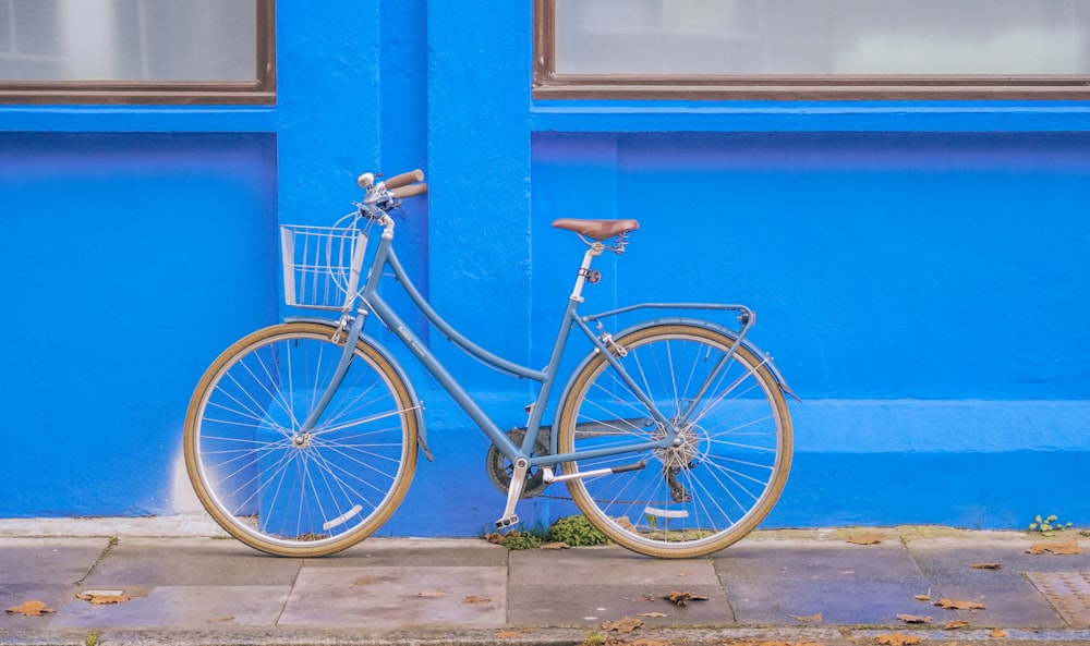 blue city bike parked beside blue painted wall