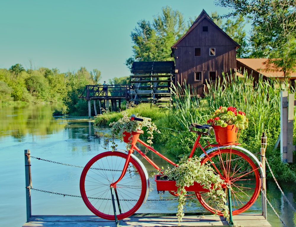 red city bike beside brown wooden fence during daytime