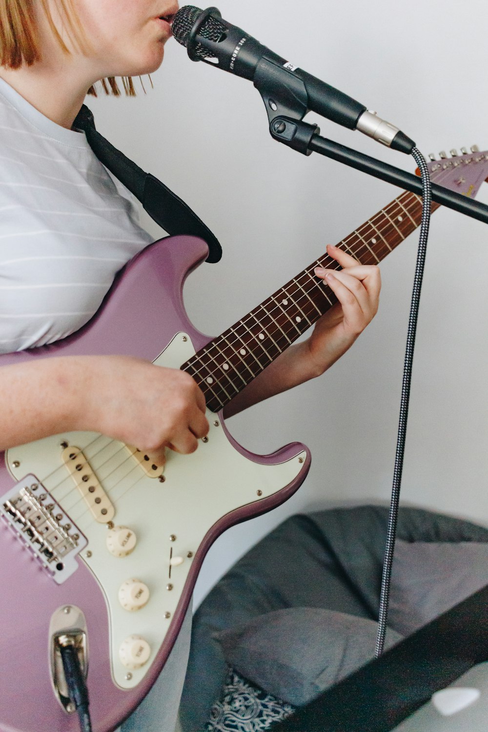 person holding red and white stratocaster electric guitar