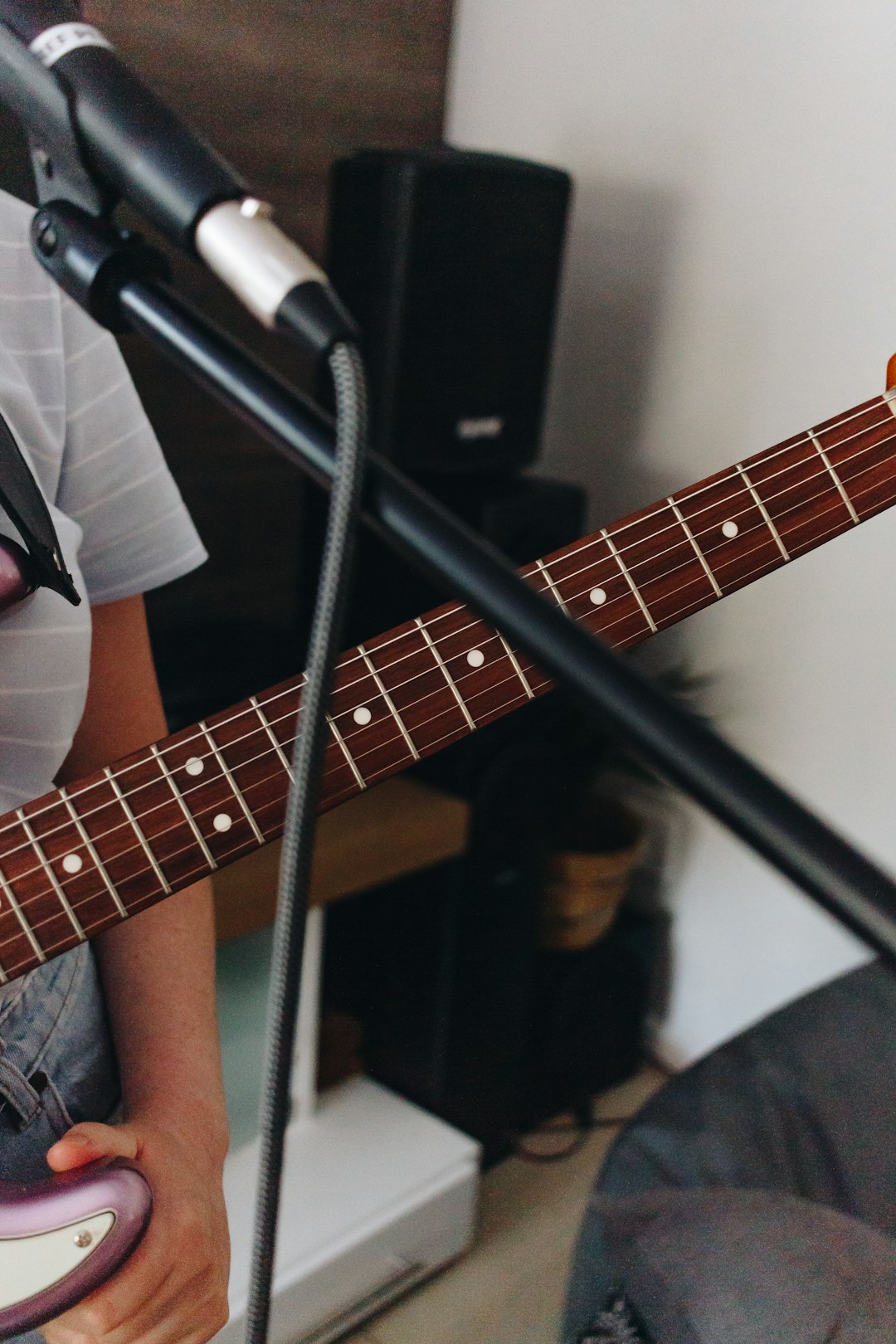 person playing guitar near microphone stand