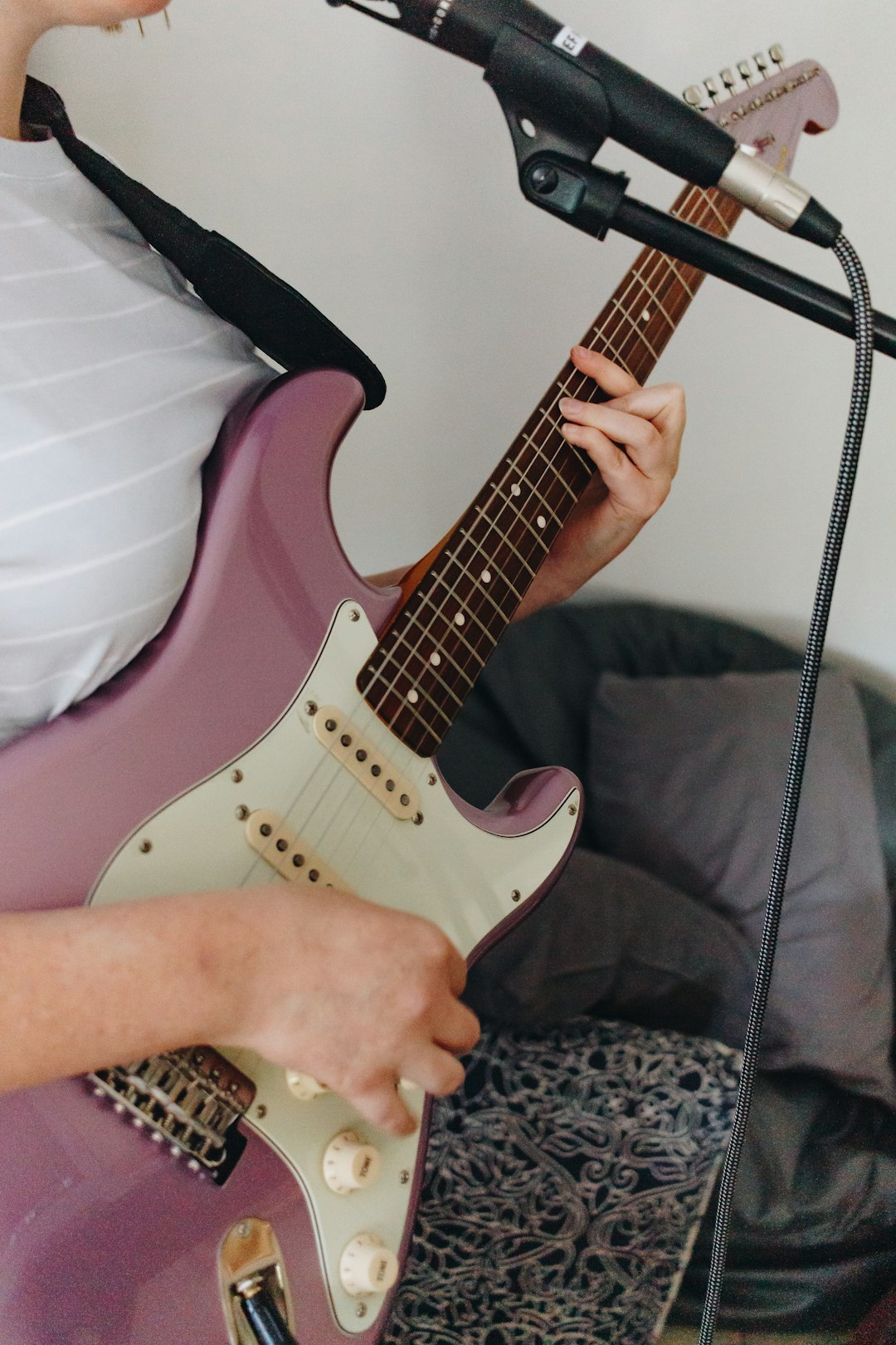 person holding pink and white electric guitar