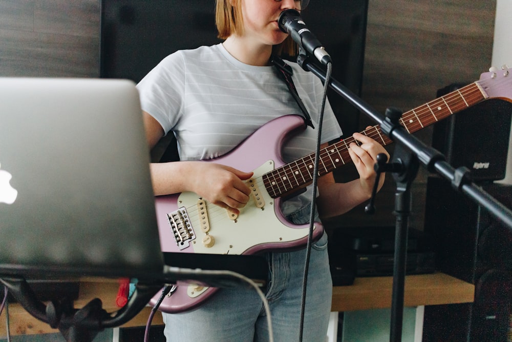 일렉트릭 기타를 연주하는 흰색 크루 넥 티셔츠를 입은 여자