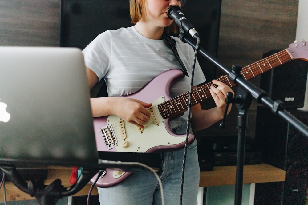 mulher na camiseta branca do pescoço da tripulação que joga a guitarra elétrica