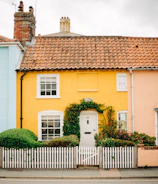 A charming cottage featuring a warm yellow chromara roof surrounded by lush greenery.