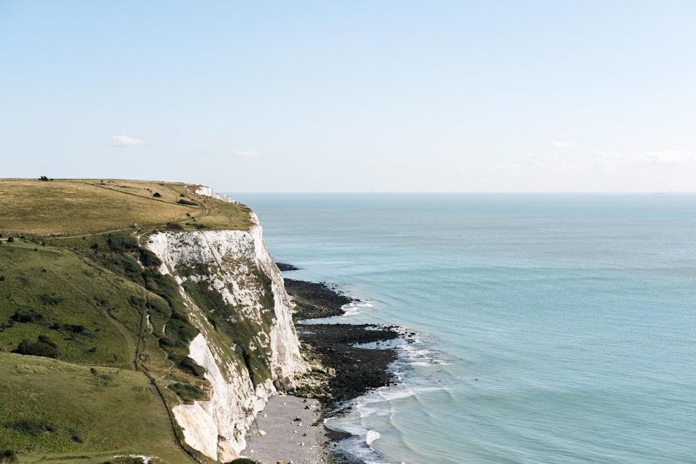 brown rocky mountain beside blue sea under blue sky during daytime