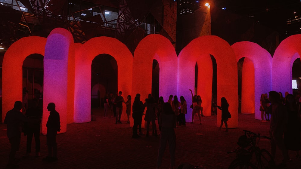 people standing near pink concrete building during nighttime