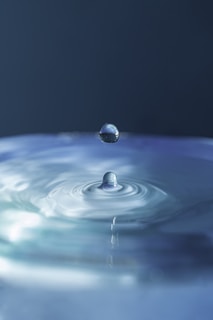 A serene water droplet splashing into a clear puddle.