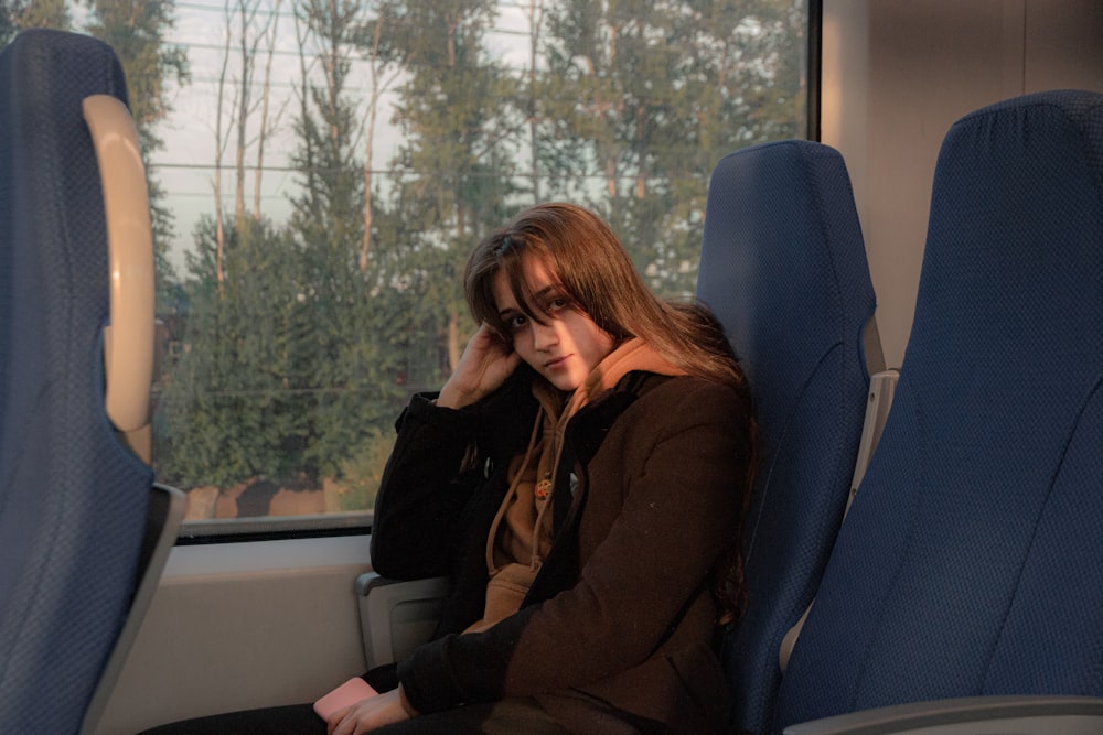 woman in black jacket sitting on blue chair