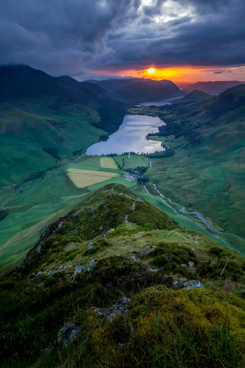 green grass field near body of water during sunset