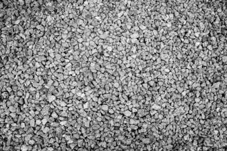 An arrangement of small, uniformly sized gravel stones, with various shades of gray due to natural variations in the rock. The texture appears rough, and the gravel covers the entire frame.