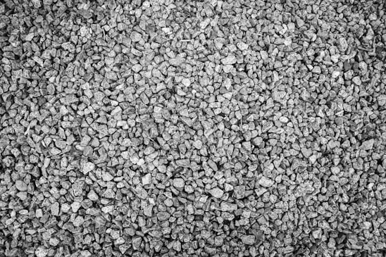 An arrangement of small, uniformly sized gravel stones, with various shades of gray due to natural variations in the rock. The texture appears rough, and the gravel covers the entire frame.