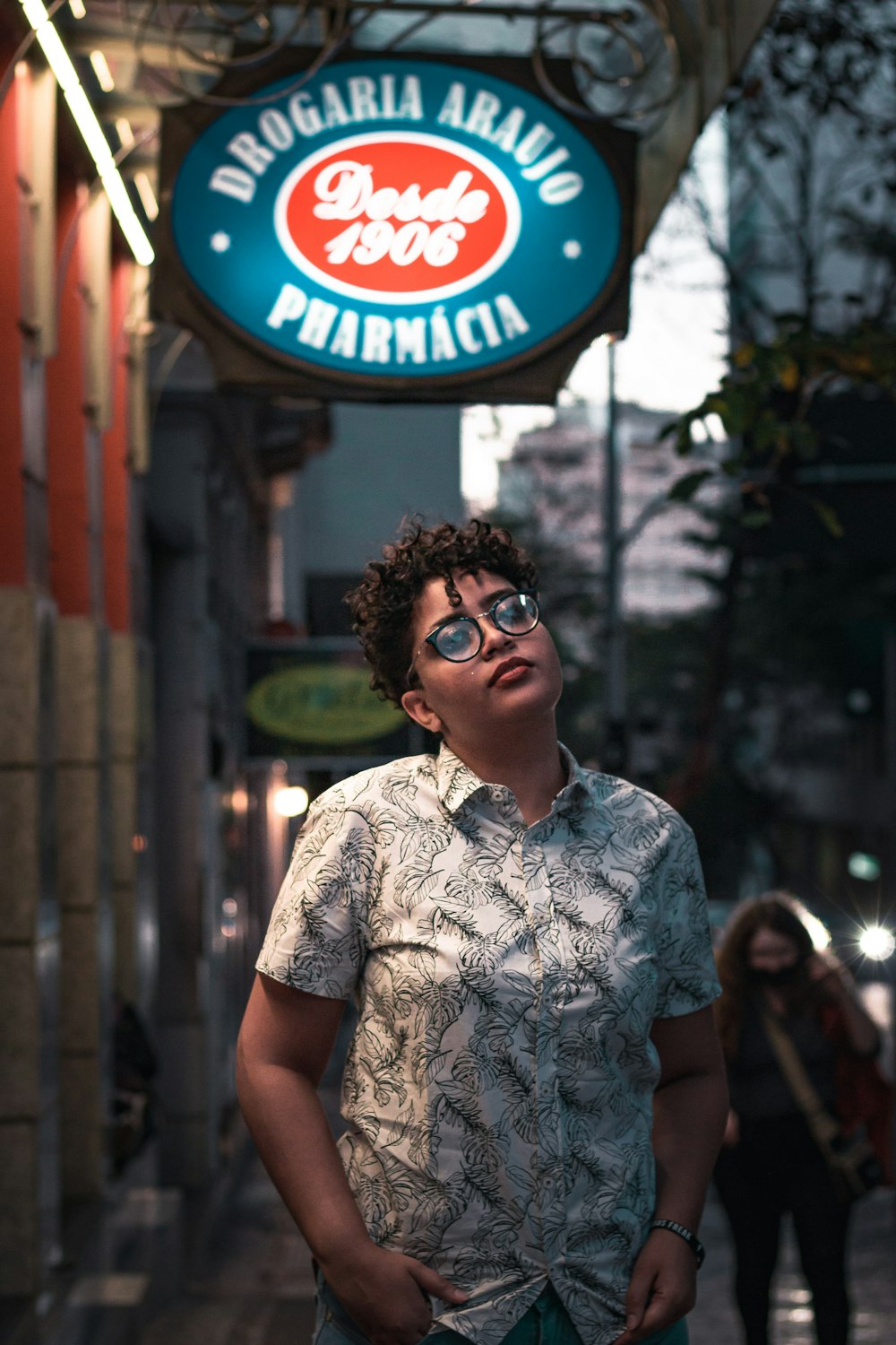 man in white and blue floral button up shirt wearing black sunglasses standing near red and