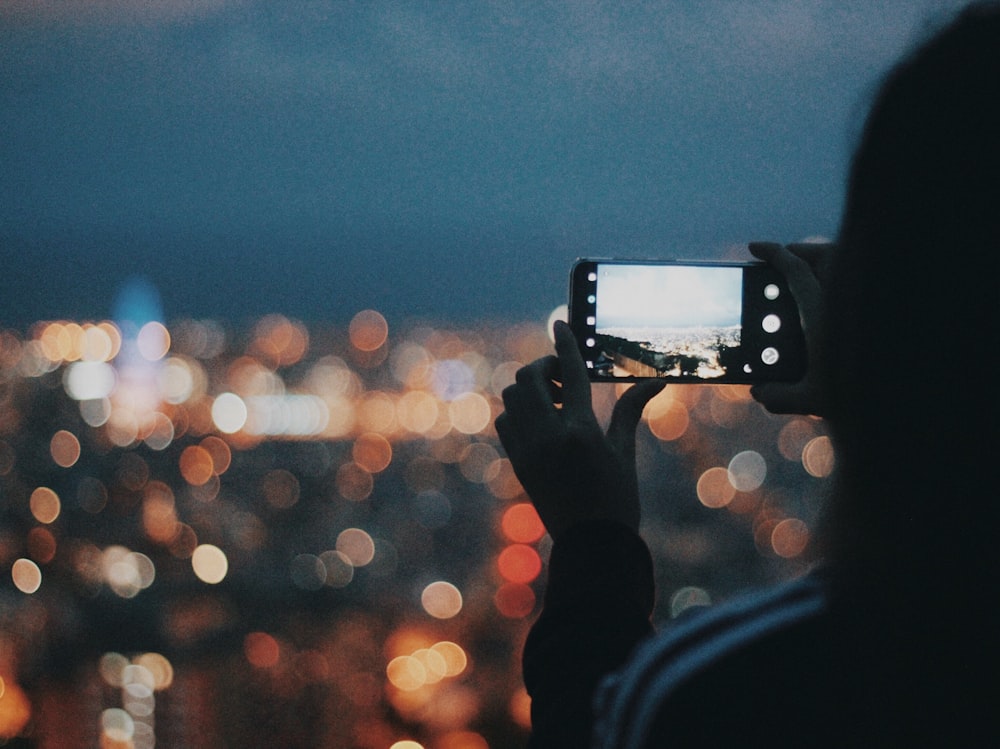 person taking photo of city lights during night time