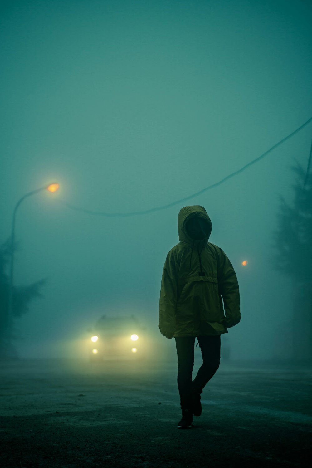 Person in braunem Kapuzenpulli, die nachts auf der Straße steht