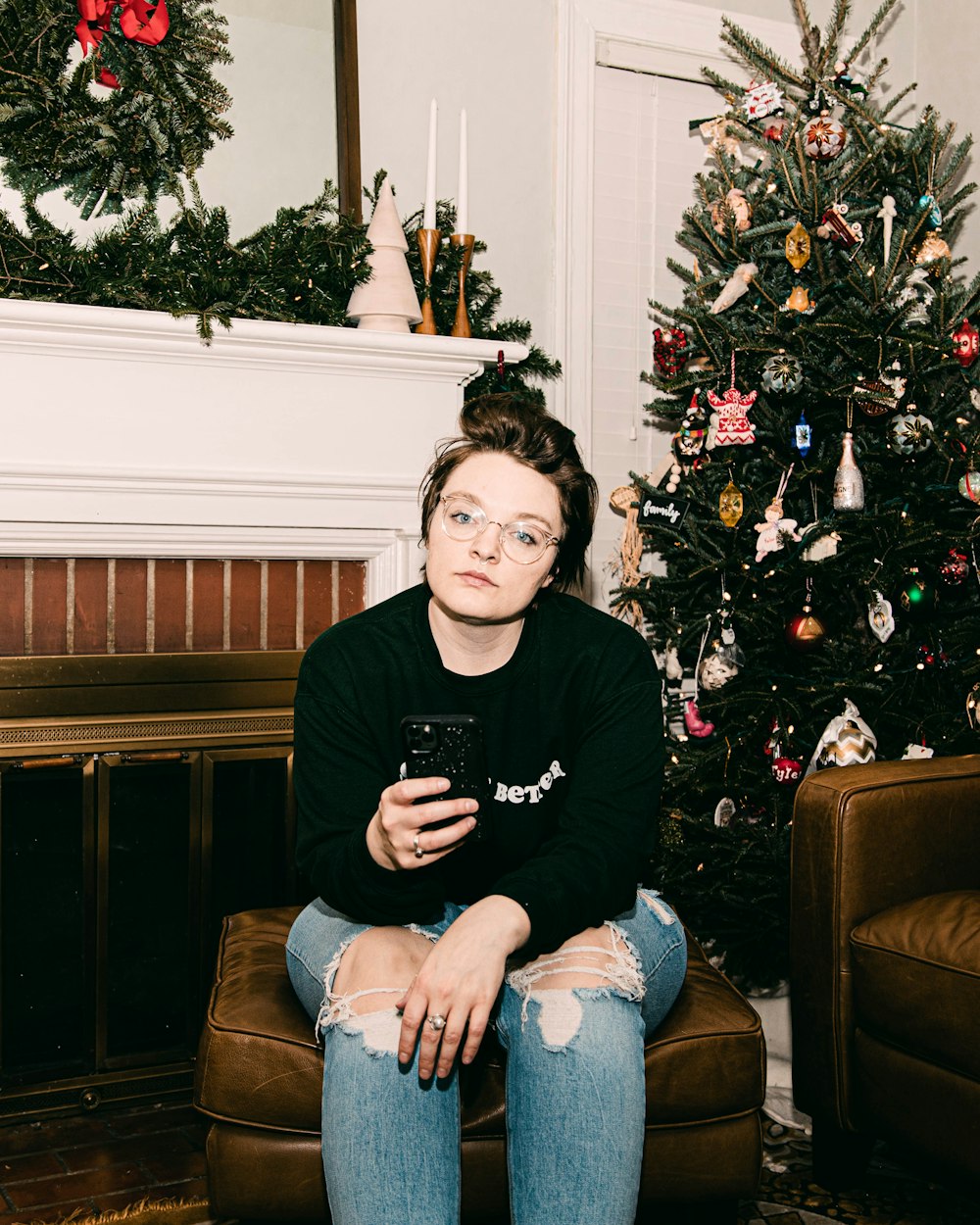 man in black crew neck t-shirt and blue denim jeans sitting on brown sofa chair