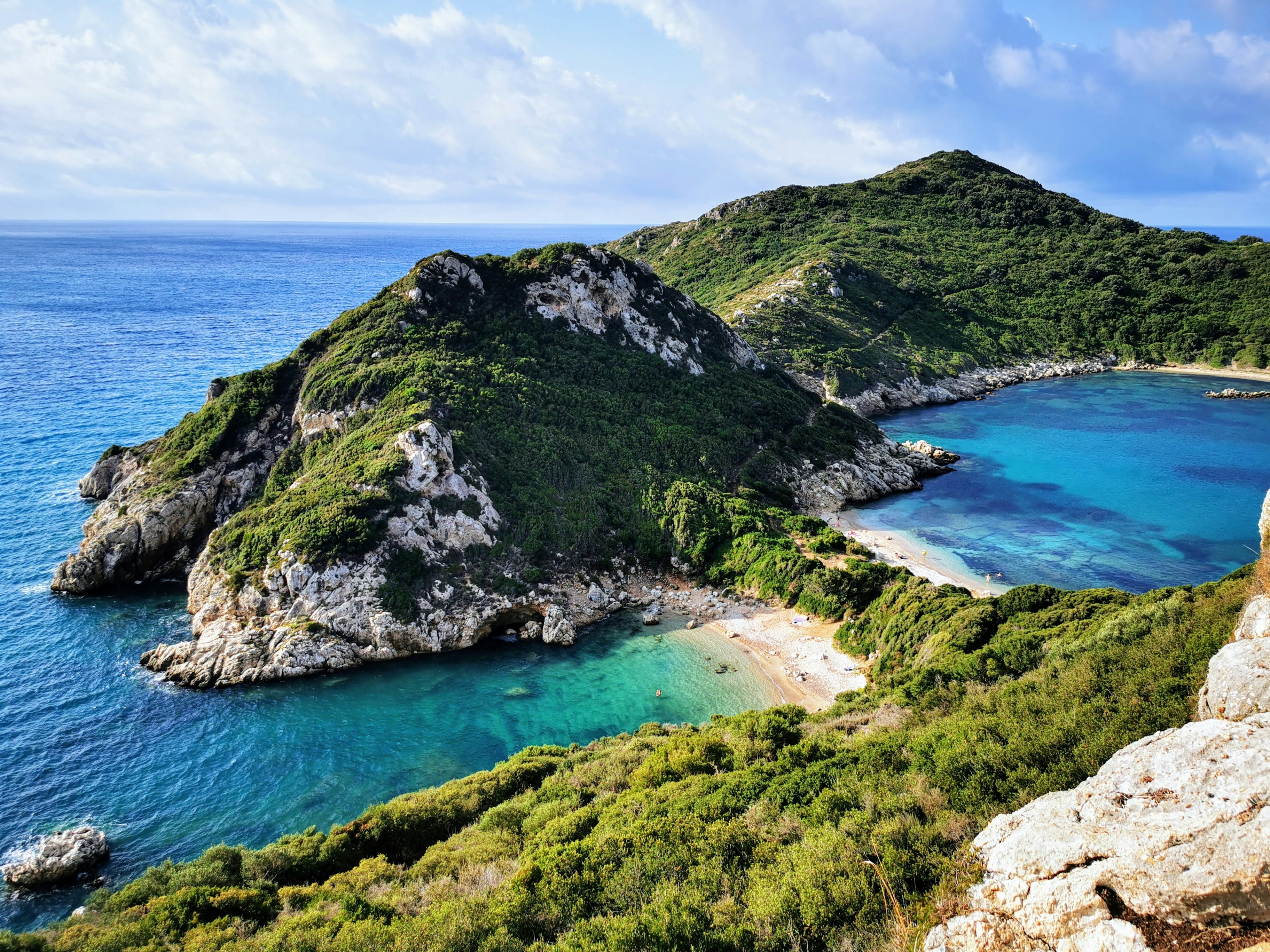 green mountain beside blue sea under blue sky during daytime, Twin bays of Porto Timoni