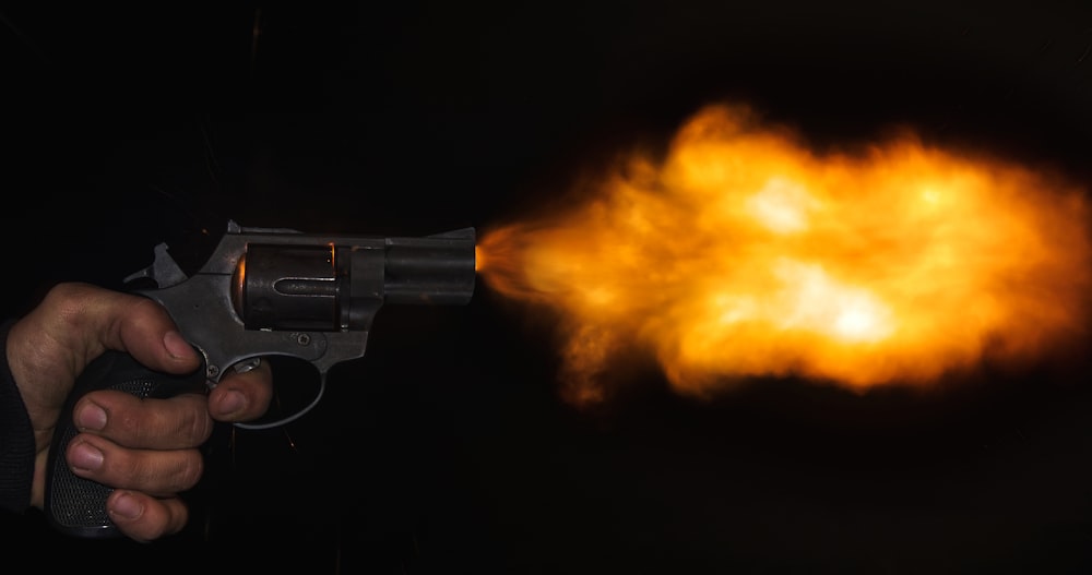 pistola revólver prateada e preta com fumaça laranja