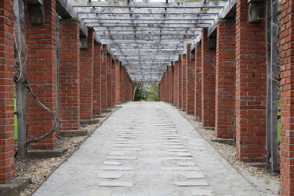gray concrete pathway between red brick wall