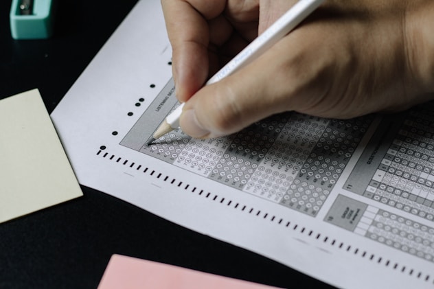 Close-up of a hand with pencil on test paper, illustrating the GRE test-taking process