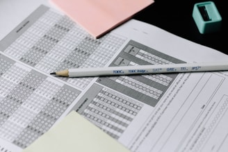 A standardized test answer sheet with multiple-choice bubbles is accompanied by a pencil and a pencil sharpener. Overlapping sheets with filled and unfilled circles indicate test preparation or completion. Colored sticky notes are placed nearby, suggesting organization or note-taking.