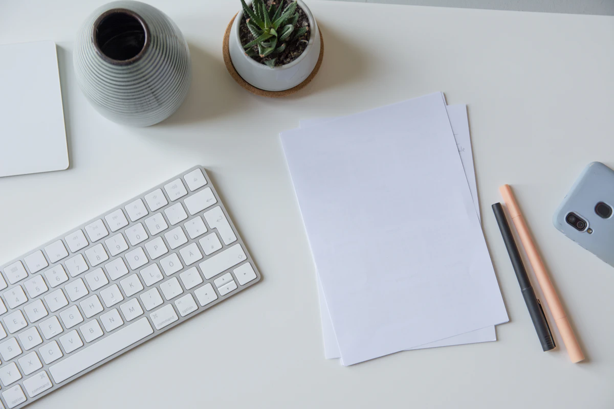 Feuilles de papier blanc posées à côté d'un clavier d'ordinateur