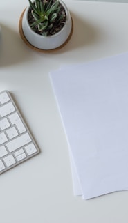 white printer paper beside white apple keyboard