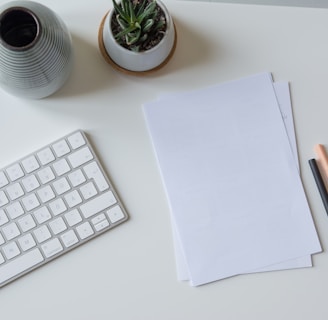 white printer paper beside white apple keyboard