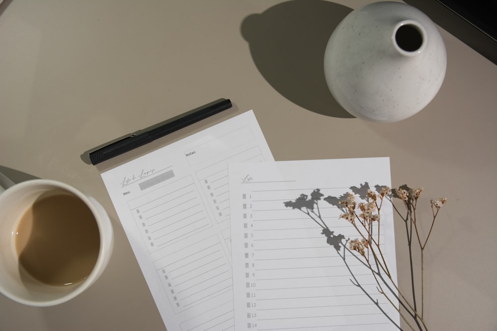 papel blanco de la impresora junto a la taza de cerámica blanca