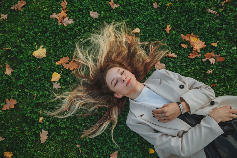 woman in blue blazer lying on green grass with yellow flowers