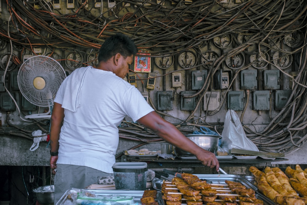 man in white crew neck t-shirt standing in front of food display