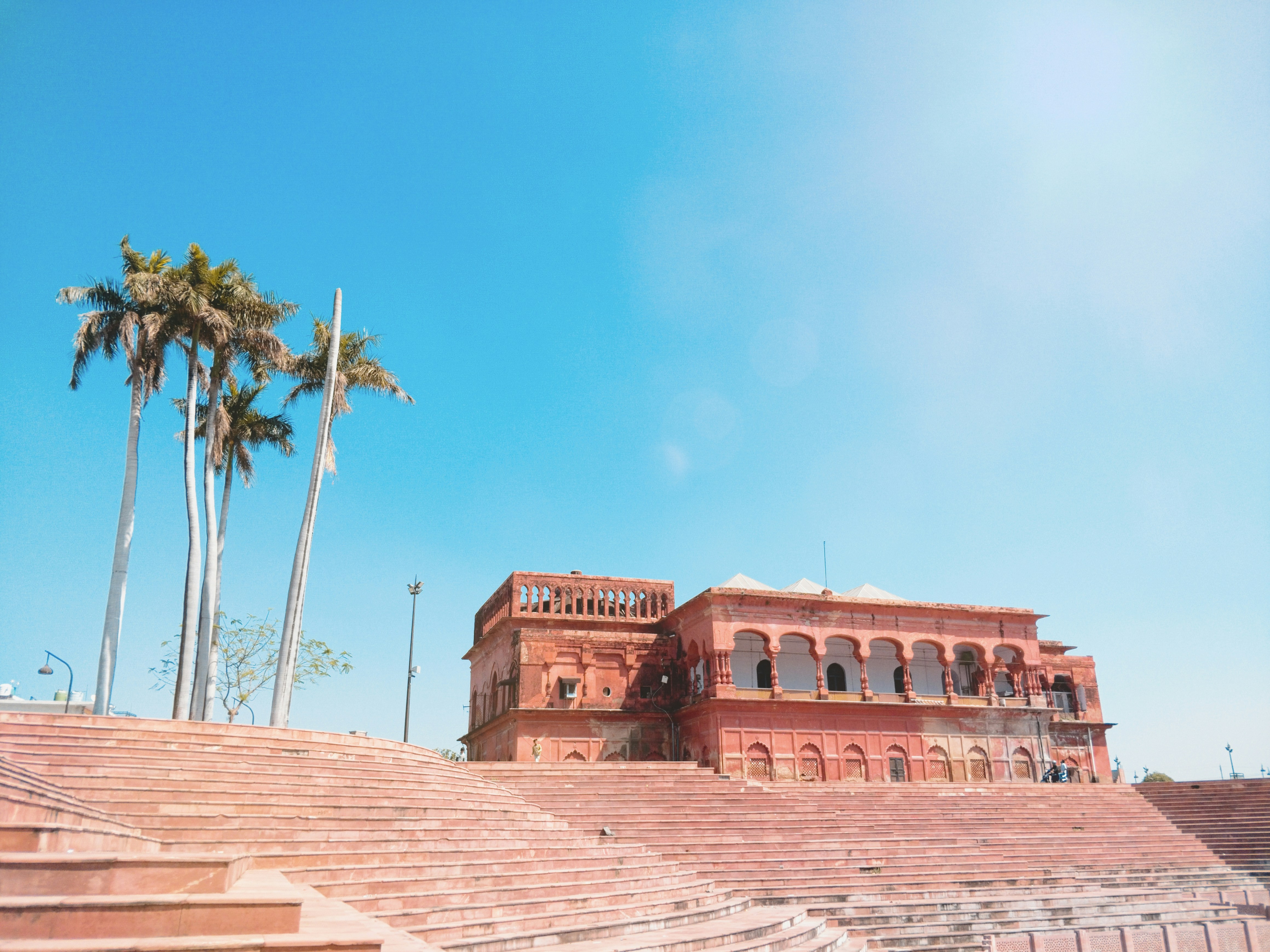 brown concrete building near palm trees under blue sky during daytime