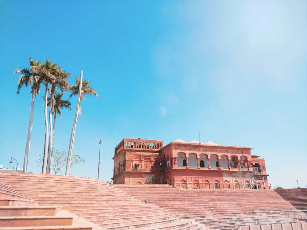 brown concrete building near palm trees under blue sky during daytime