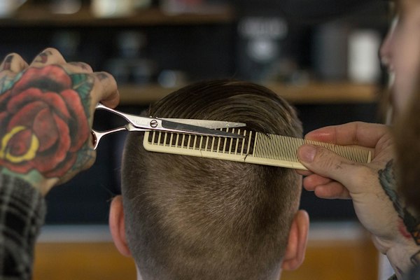 Barber cutting over a comb with shears