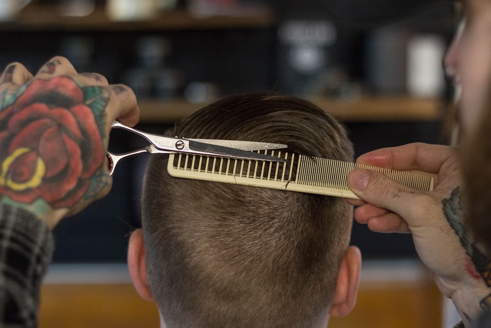 persona che tiene il pettine dei capelli bianco e oro