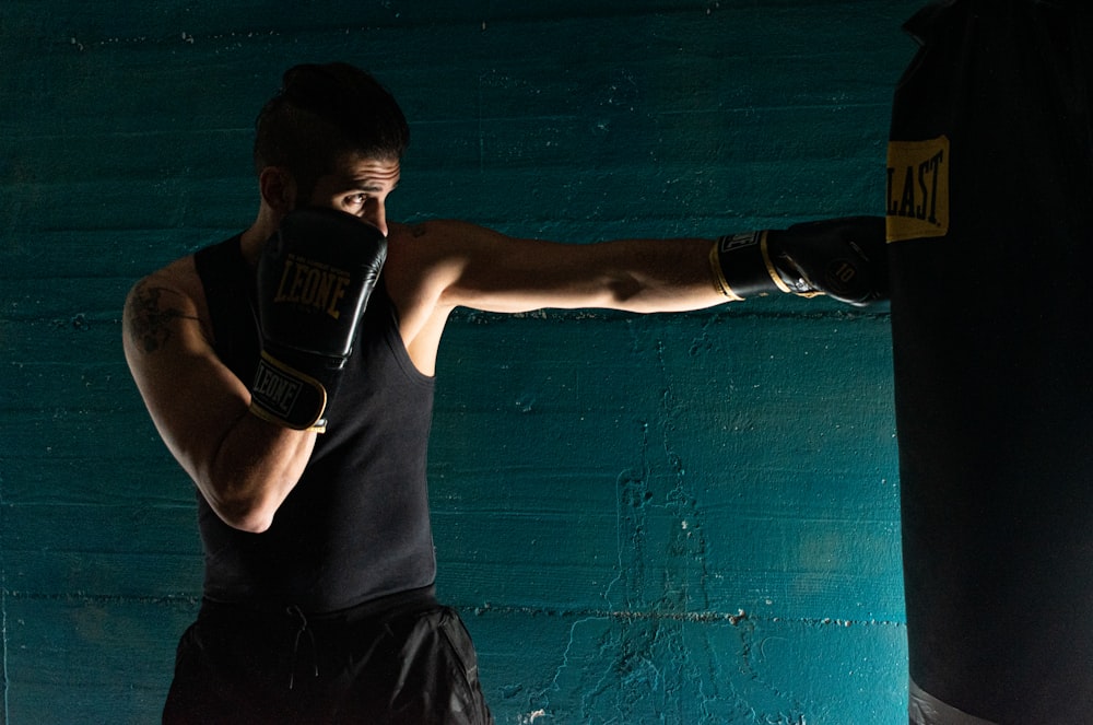 Hombre con camiseta sin mangas negra y pantalones cortos negros con guantes de boxeo negros