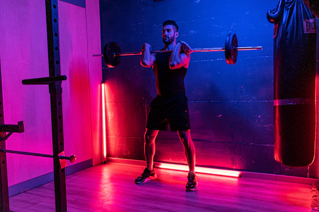 A dynamic gym scene blending ancient Greek mythology elements with modern fitness, showing a hero lifting weights surrounded by glowing mythical symbols.
