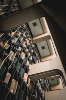 An interior architectural structure features a complex wall design with three-dimensional geometric patterns. The ceiling has a grid-like structure with recessed lights, and the composition creates an abstract, futuristic appearance.