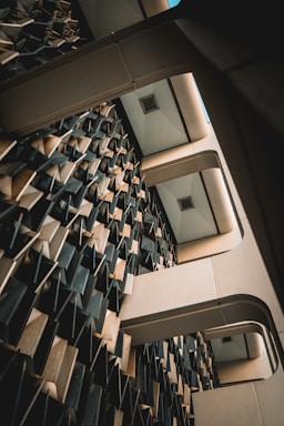 An interior architectural structure features a complex wall design with three-dimensional geometric patterns. The ceiling has a grid-like structure with recessed lights, and the composition creates an abstract, futuristic appearance.