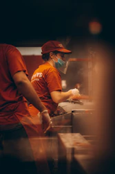 man in orange crew neck t-shirt and black pants wearing orange cap