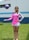 woman in pink long sleeve shirt and white skirt standing on green grass field during daytime